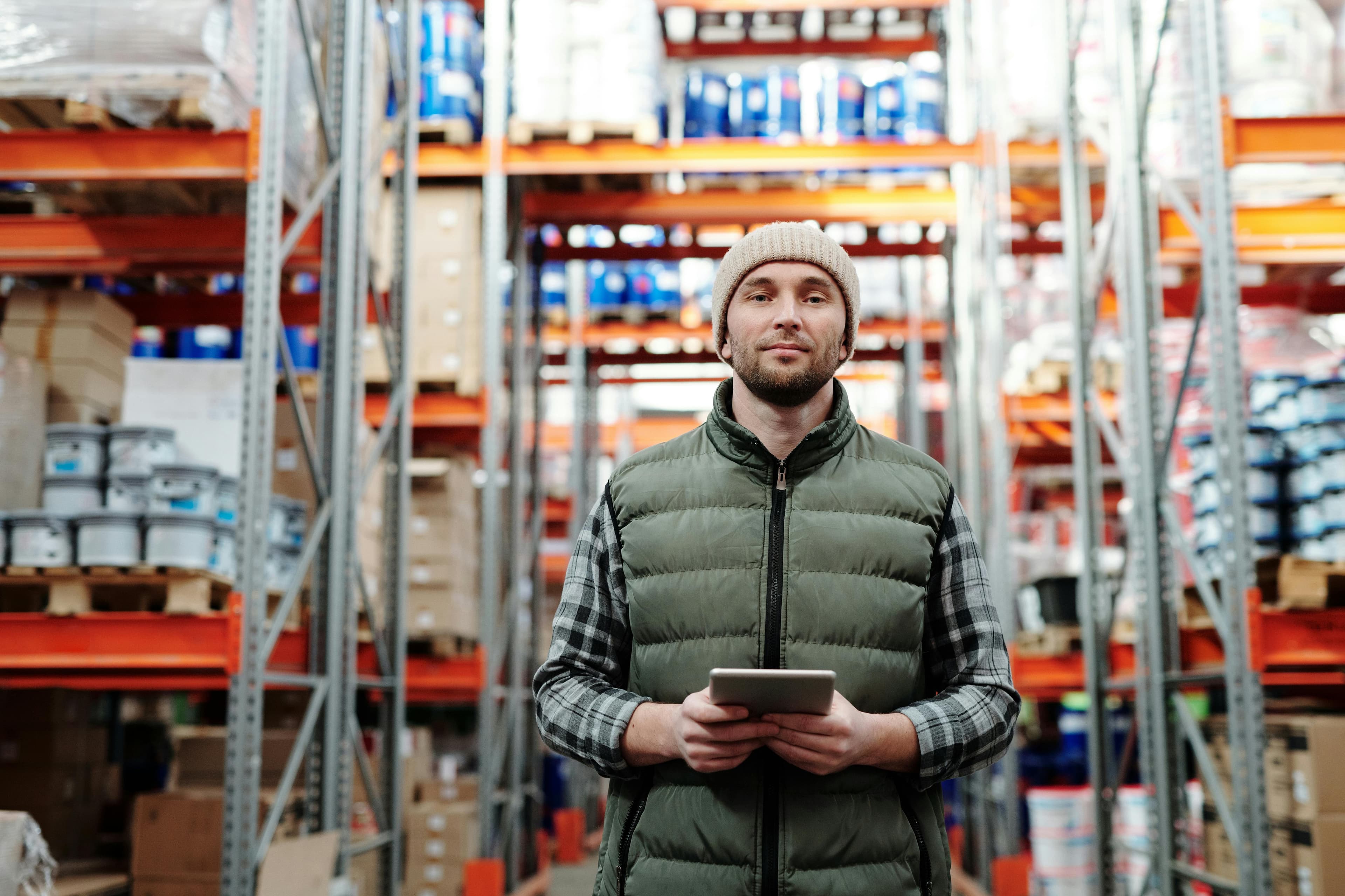 Warehouse operator using a tablet in front of inventory shelves.