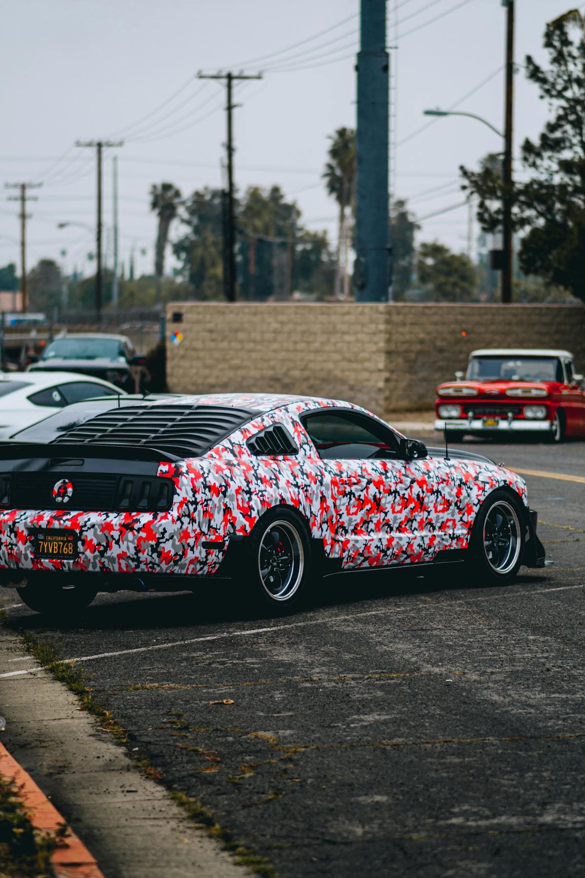 Sports coupe finished in a red white and black camouflage wrap.